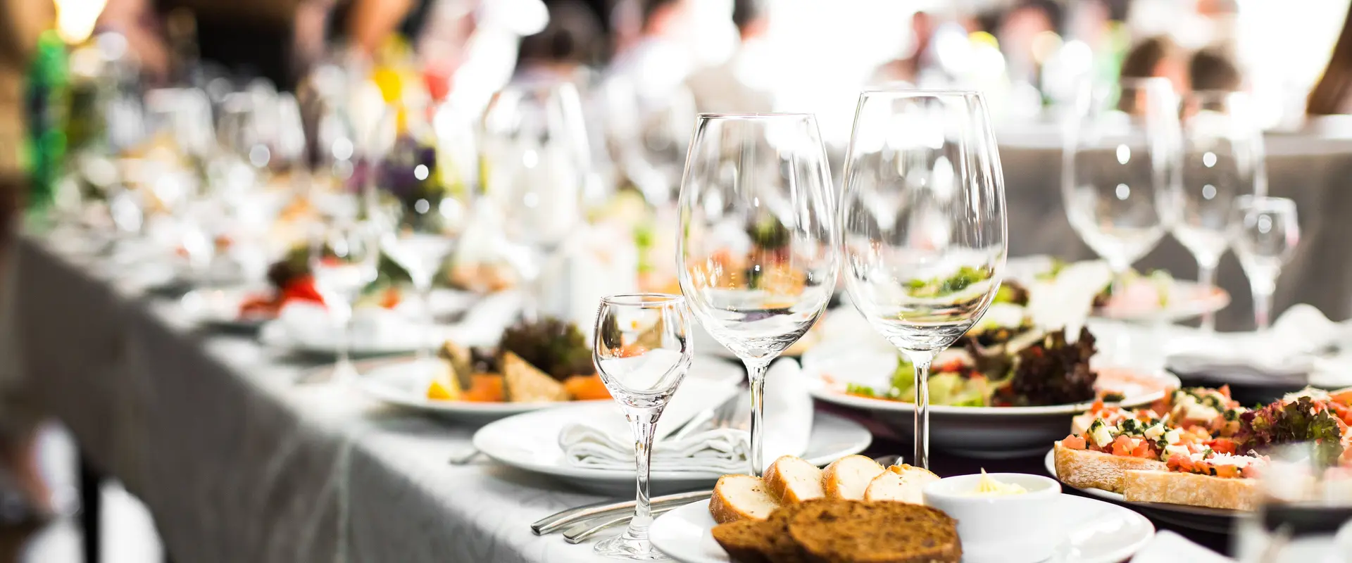 Fein gedeckte Tafel mit Weingläsern, Speisen. Weisse Teller und Weisse Tischdecke.